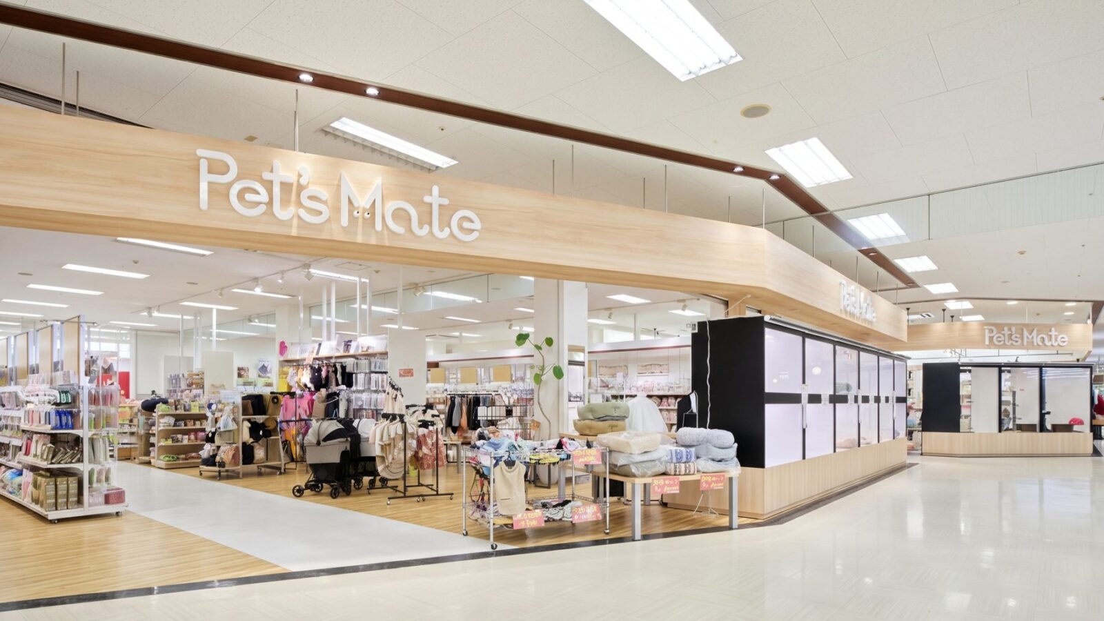 木目の大きなサインと白いショーケースが並ぶ、商業施設内のペットショップ