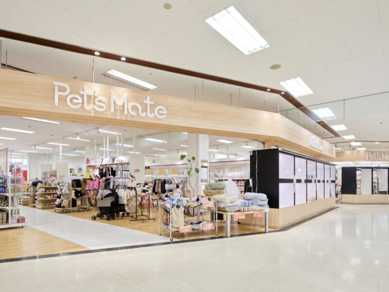 木目の大きなサインと白いショーケースが並ぶ、商業施設内のペットショップ